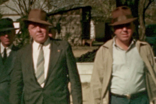 Three white men in 1940s garb walking outside.